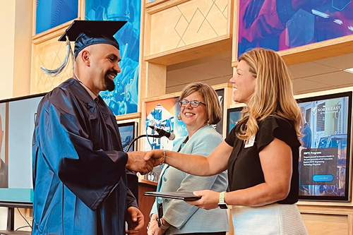 College leaders congratulate a student graduate in the Trades Atrium