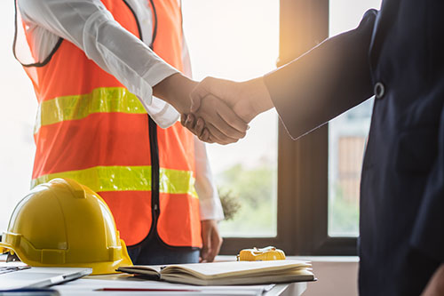 A person wearing protective equipment shakes hands with their employer