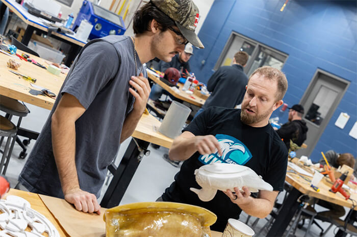 A student discusses a plastic prototype with an instructor