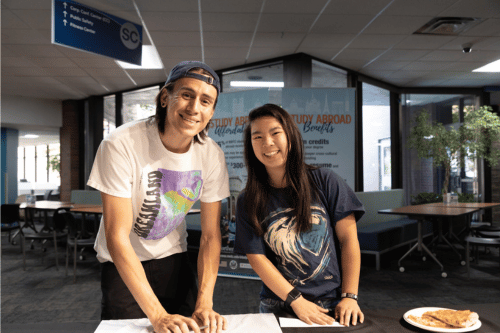 Two students standing by a resource table