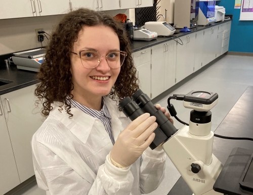 Justyna Kakol using a microscope in the lab. 