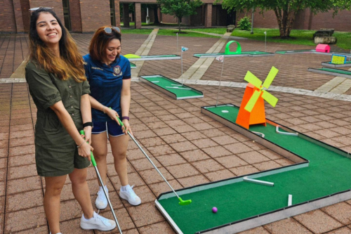 Two students playing mini golf
