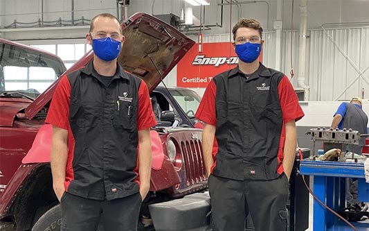 Automotive students standing in front of car with hood up