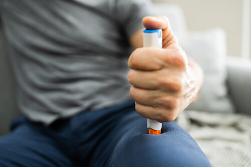 A person injects an epi pen into their thigh