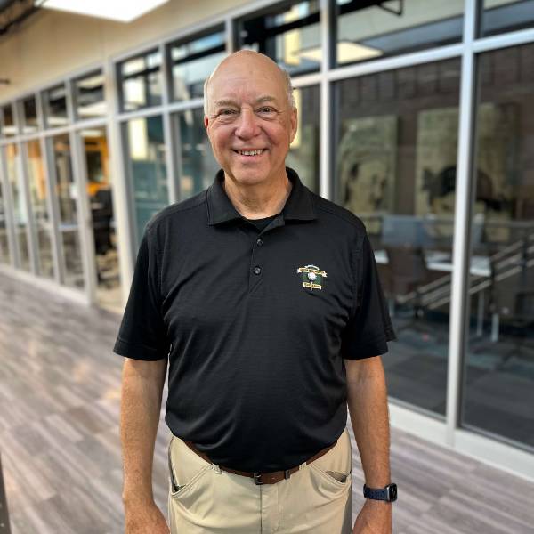 Joe Langer, standing in the NWTC College of Business, smiles, facing camera.
