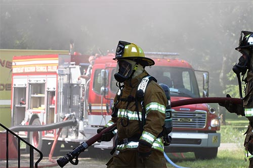 Firefighter in gear standing in front of fire truck