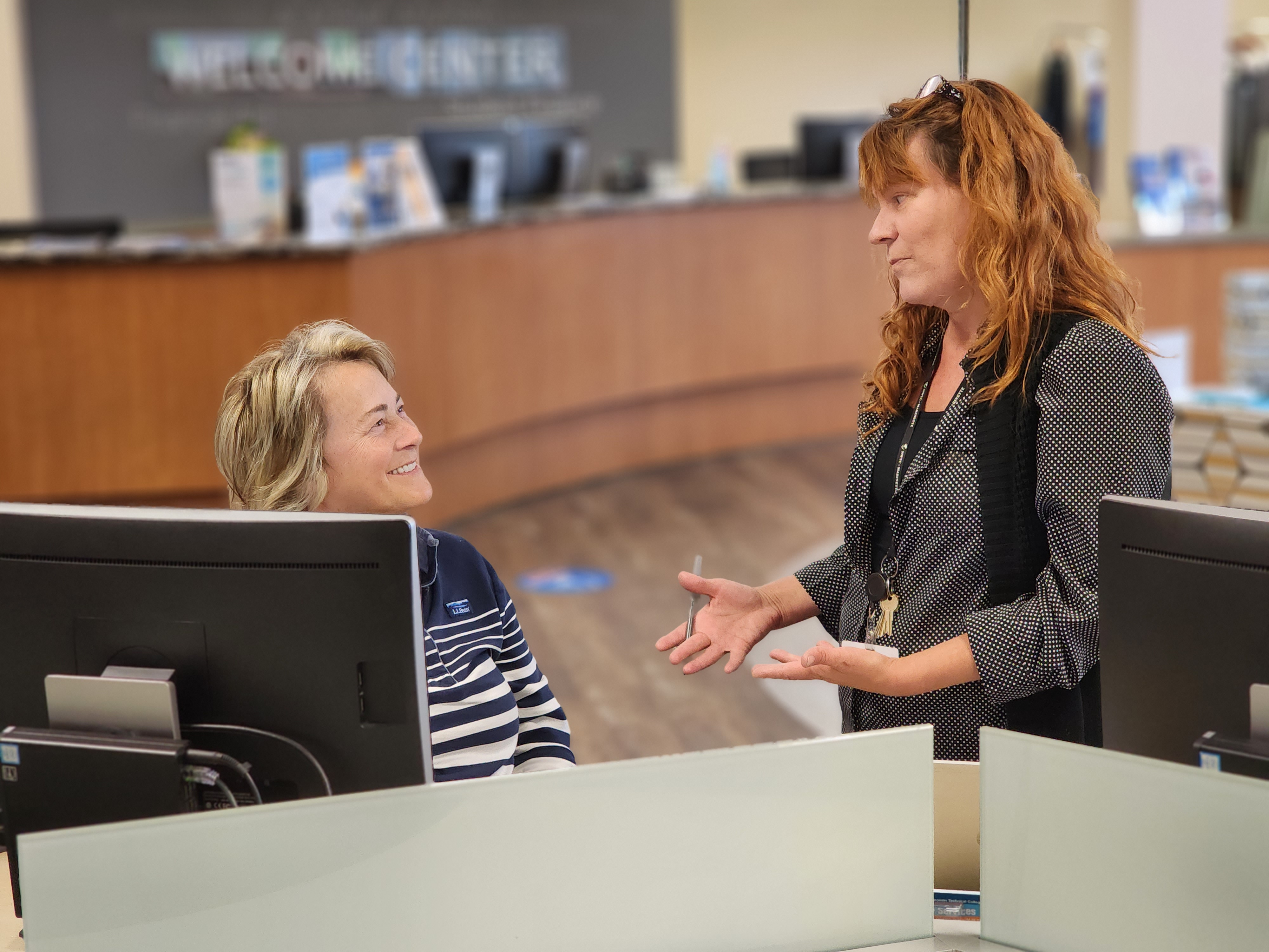 staff and student discuss classes at desk