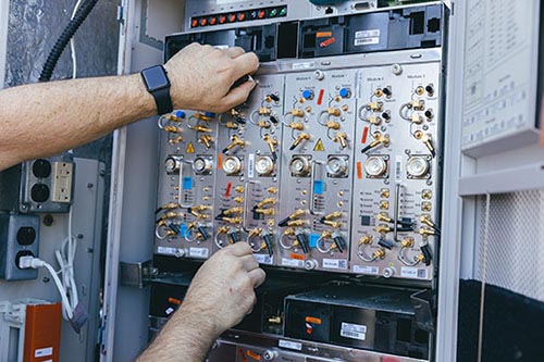 Hands adjusting wires on equipment panel