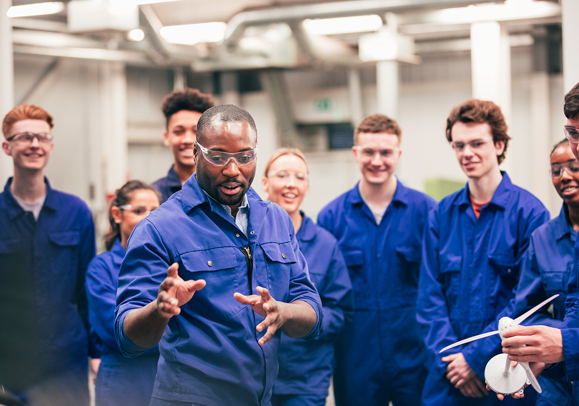 A manager leads a group of students on a tour of a manufacturing plant