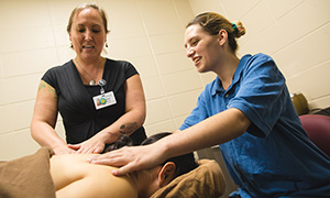 Massage therapy students work with an instructor