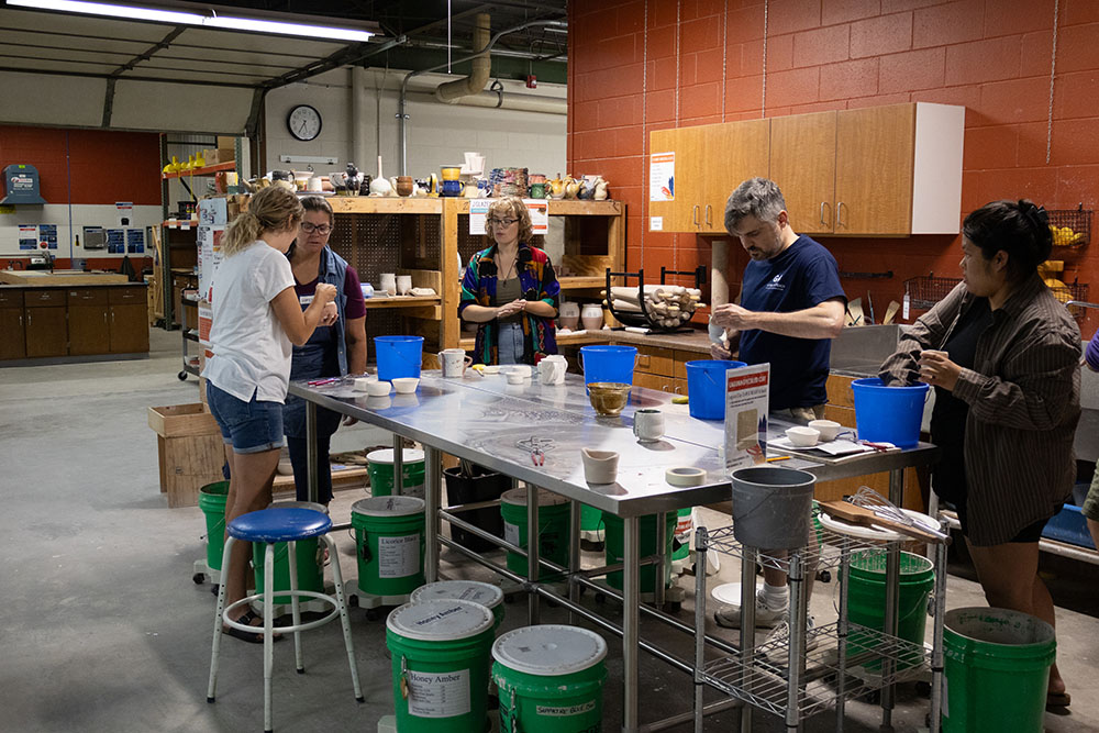 students glazing pottery