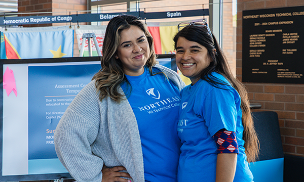 Two staff members welcoming students back to college