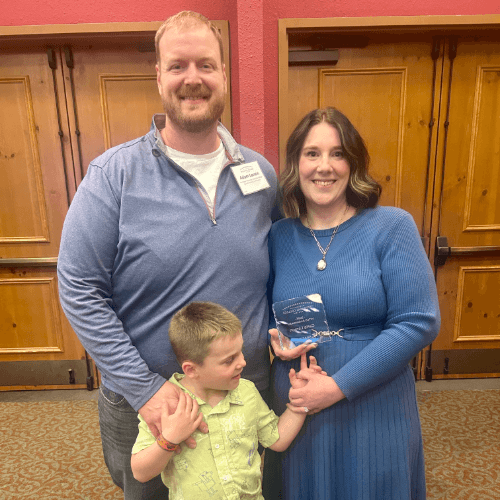 A man and a woman looking at the camera with a boy in between them.