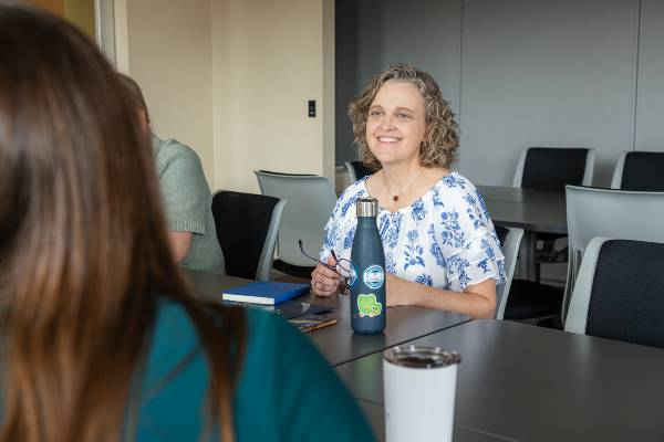 Jennifer Flatt sitting at a table with colleagues in conference room