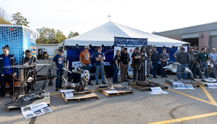 Welding Rodeo participants stand in front of event banner