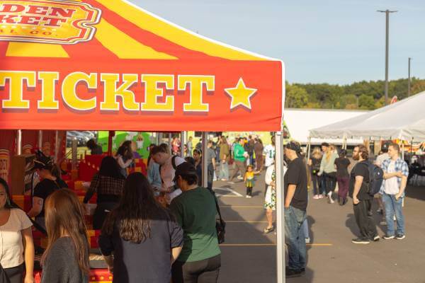 Large number of people standing in line for carnival games at Fall Fest