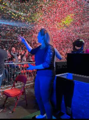 Erin Cooper standing in darkened theater in front of an audience; colorful confetti in the air
