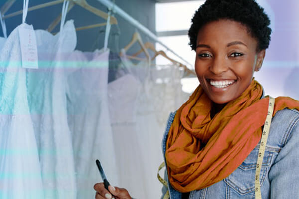 Woman holding a pen and measuring tape inside a dress shop