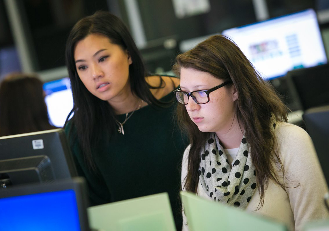 An advisor helps a student on a computer