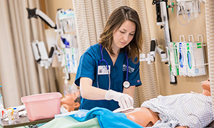 A student works on a patient simulator in the nursing lab