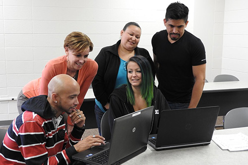Students gather around a computer in a GED class