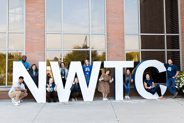 Career coaches pose by the NWTC welcome sign