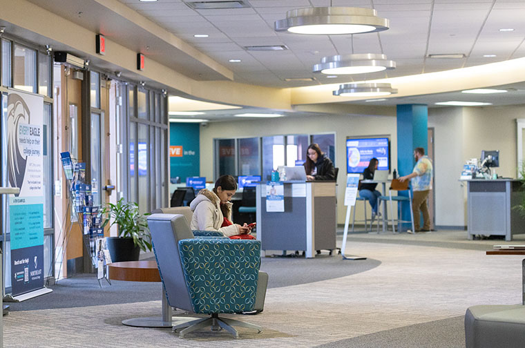 Student waits in NWTC welcome center while employee looks at computer screen