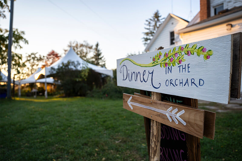A sign directs wedding guests to dinner in the orchard