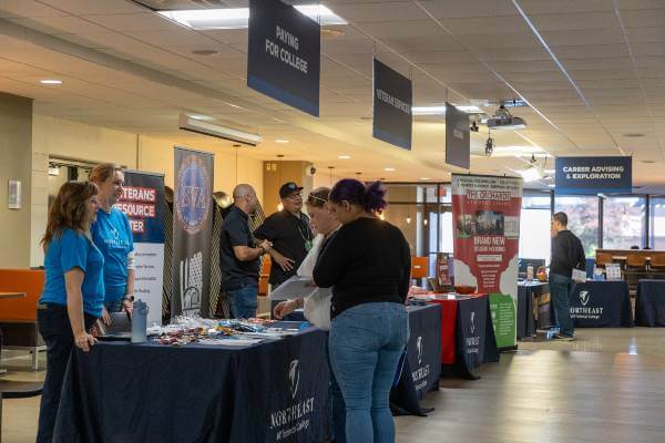 two NWTC female staff members talk to two open house attendees