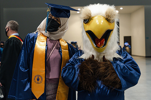 An honors student poses with the NWTC Eagle at commencement