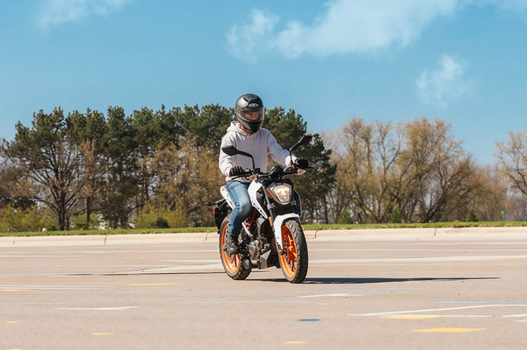 Student driving motorcycle in parking lot