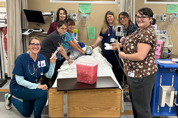 The friendly staff at NWTC Marinette pose around a patient simulator in the nursing lab