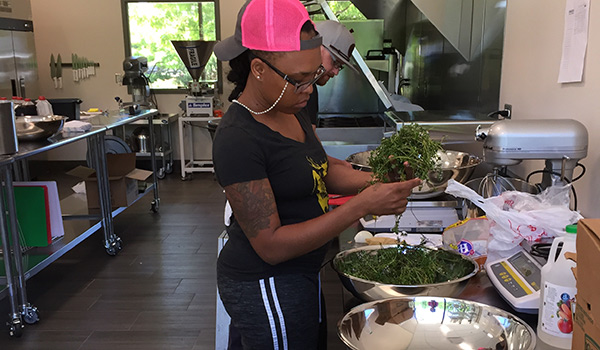 A student at the Shared Kitchen mixes salad in a bowl