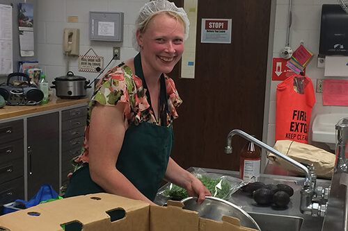 A kitchen producer cleans dishes in the shared use kitchen