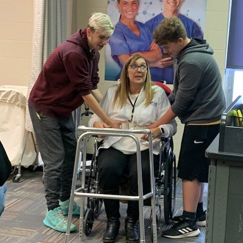 Woodland students help a patient in a walker