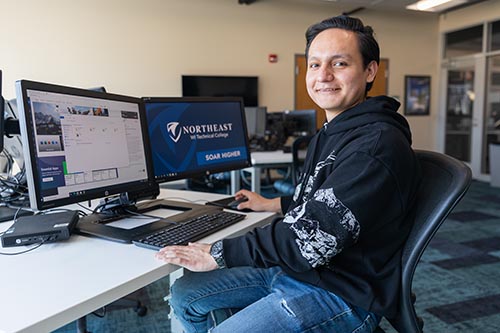 Student posing in front of computer monitors