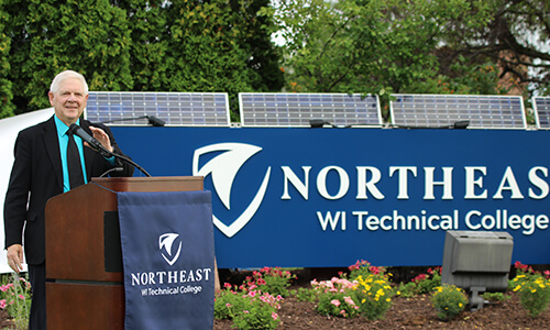 College President, Dr. Rafn standing in front of the new logo
