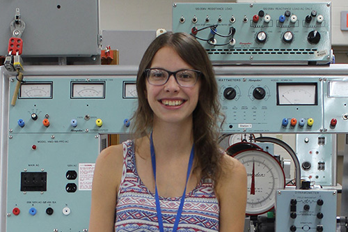A female student stands in from of a control panel