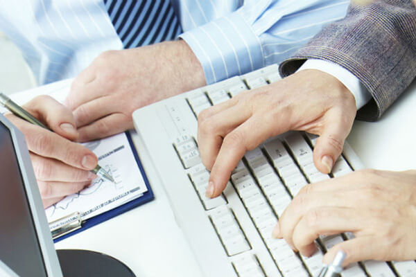 Two people sit side by side while typing