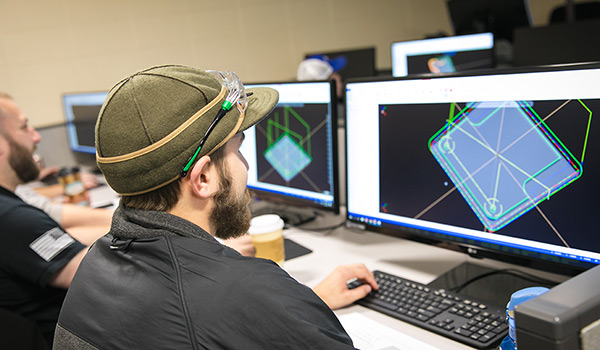 A student wearing a hat works on CAD