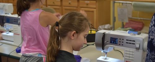 two young girls at a sewing machine