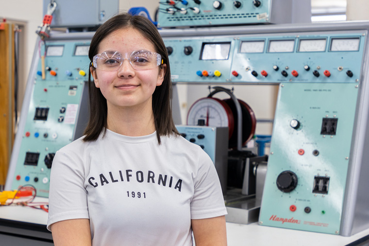 Smiling student stands in front of machines