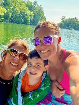 Mary Beth Boettcher with daughter and grandson at the lake, smiling at camera