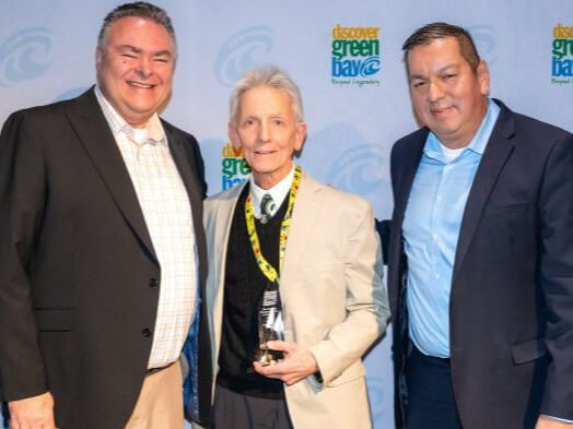 Jerry Lintz, holding an award, standing with two men from Discover Green Bay