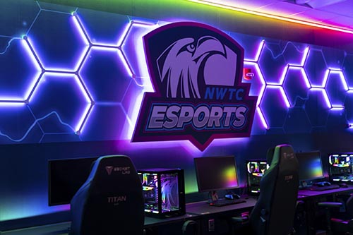 NWTC eSports Zone logo behind row of computers and keyboards
