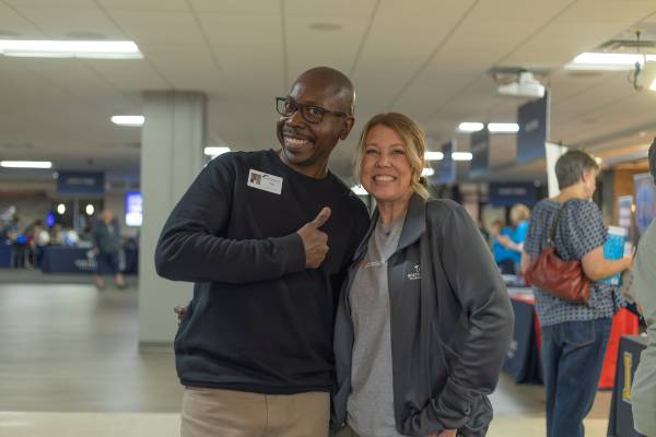 two NWTC staff members stand together, smiling at camera; during NWTC open house