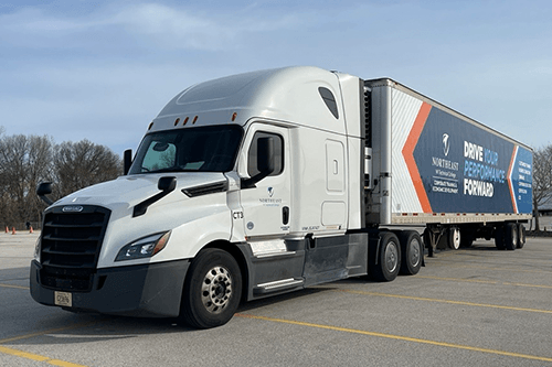 White semi‑truck with a branded trailer parked in a lot, displaying “Northeast Wisconsin Technical College” and “Drive Your Performance Forward.”